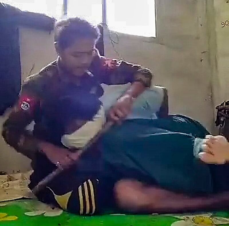 မျက်နှာတွင်အဝတ်စည်းကာ လက်နောက်ပြန်ကြိုးတုပ်ပြီး ဖမ်းဆီးခံထားရသည့် အရပ်သားကို စစ်ကောင်စီတပ်သားက ညှဉ်းပန်းနှိပ်စက်နေစဉ်။ (RFA screenshot from video)