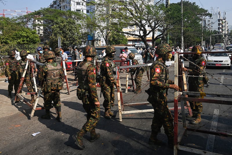 Soldiers prepare to block a road in front of the Central Bank of Myanmar in Yangon on Feb. 15, 2021.